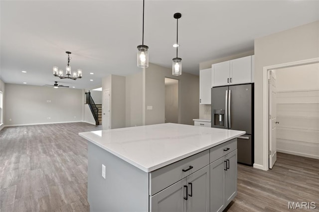 2213 Rule Ave, Maryland Heights, MO 63146 - kitchen featuring stainless steel fridge with ice dispenser, a center island, wood finished floors, decorative light fixtures, and light stone counters