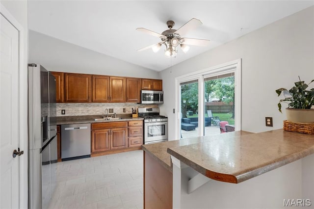 15 Ann Dr, Saint Peters, MO 63376 - kitchen with appliances with stainless steel finishes, a peninsula, tasteful backsplash, brown cabinets, and a ceiling fan
