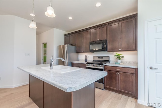 9 Vera Pl, Saint Charles, MO 63303 - kitchen featuring appliances with stainless steel finishes, light wood-style flooring, light countertops, dark brown cabinetry, and a center island with sink