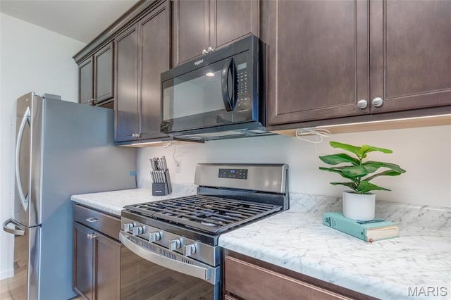 9 Vera Pl, Saint Charles, MO 63303 - kitchen with appliances with stainless steel finishes, dark brown cabinets, light stone countertops, and light wood-type flooring