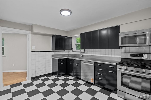 7315 Ahern Ave, University City, MO 63130 - kitchen with dark cabinets, appliances with stainless steel finishes, light flooring, stainless steel countertops, and tile walls