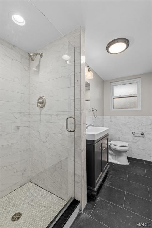 7315 Ahern Ave, University City, MO 63130 - full bath with tile walls, a shower stall, tile patterned floors, vanity, and wainscoting