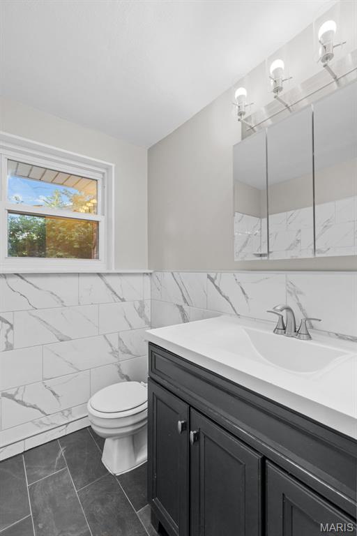 7315 Ahern Ave, University City, MO 63130 - bathroom with tile walls, vanity, and wainscoting