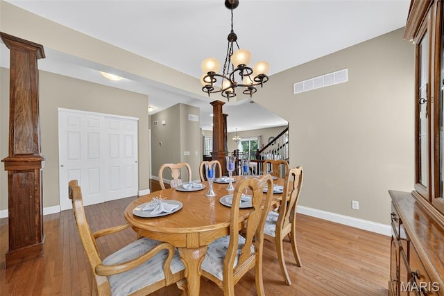 1304 Forest Way, Wentzville, MO 63385 - dining space with a chandelier, light wood finished floors, ornate columns, arched walkways, and stairs
