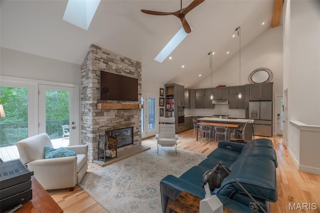 2740 Tyrol View Ct, Innsbrook, MO 63390 - living area with a skylight, high vaulted ceiling, light wood-type flooring, a ceiling fan, and a stone fireplace