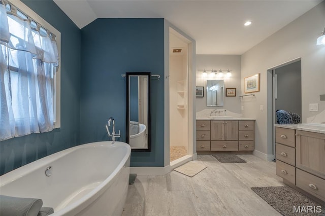 2740 Tyrol View Ct, Innsbrook, MO 63390 - bathroom with a freestanding bath, vanity, wood finished floors, vaulted ceiling, and walk in shower