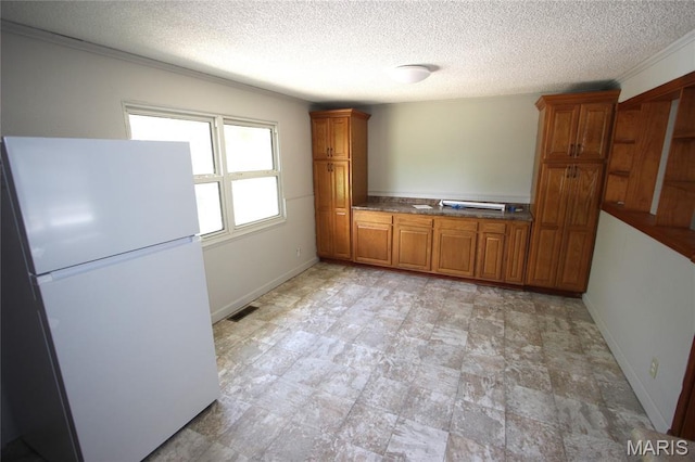 420 Lake Dr, Bonne Terre, MO 63628 - kitchen with freestanding refrigerator, brown cabinetry, a textured ceiling, and crown molding