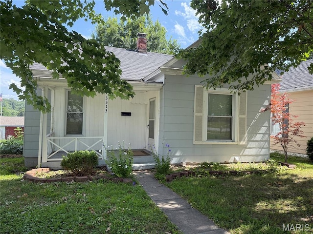 3313 Saint Charles St, Hannibal, MO 63401 - bungalow featuring a chimney, roof with shingles, a front lawn, and covered porch