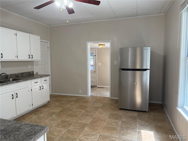 3313 Saint Charles St, Hannibal, MO 63401 - kitchen featuring freestanding refrigerator, a ceiling fan, dark countertops, white cabinets, and ornamental molding