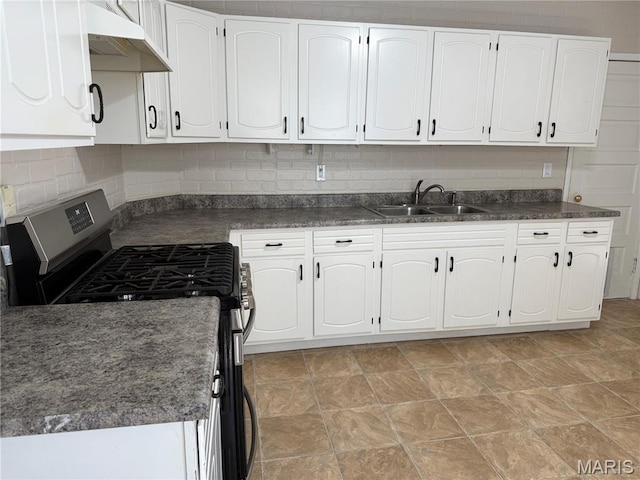 3313 Saint Charles St, Hannibal, MO 63401 - kitchen with stainless steel gas stove, under cabinet range hood, dark countertops, white cabinetry, and decorative backsplash
