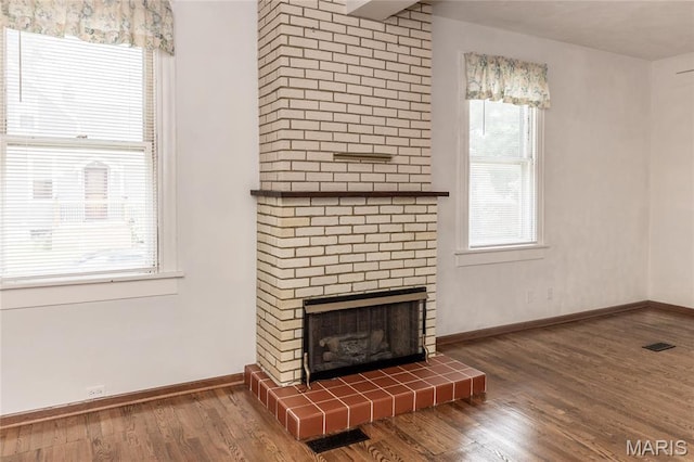 711 Erskine Ave, Lemay Township, MO 63125 - unfurnished living room with wood finished floors, plenty of natural light, and a fireplace