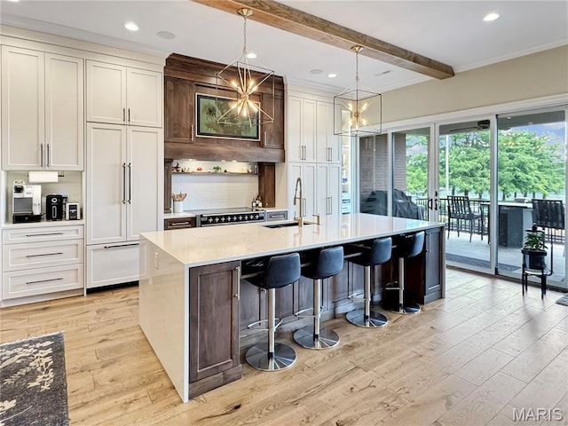 4 Market St, Washington, MO 63090 - kitchen featuring light wood-type flooring, beam ceiling, an island with sink, backsplash, and light countertops