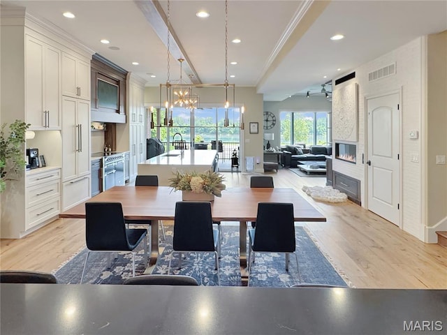 4 Market St, Washington, MO 63090 - dining space with light wood-type flooring, crown molding, a chandelier, recessed lighting, and a fireplace
