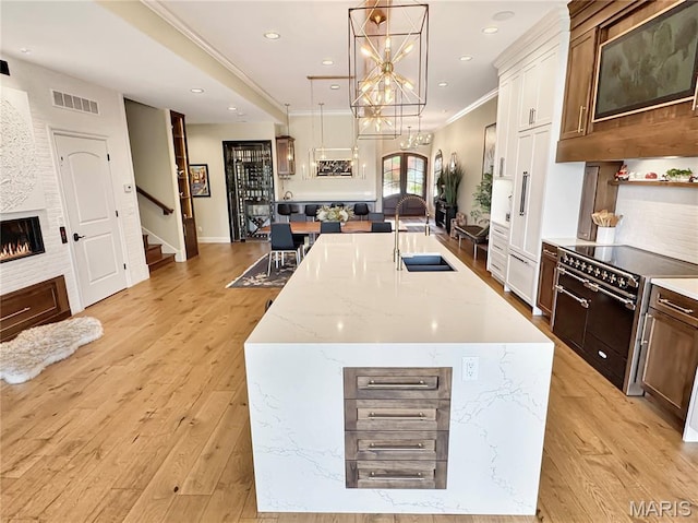 4 Market St, Washington, MO 63090 - kitchen with double oven range, an island with sink, pendant lighting, light stone countertops, and light wood finished floors