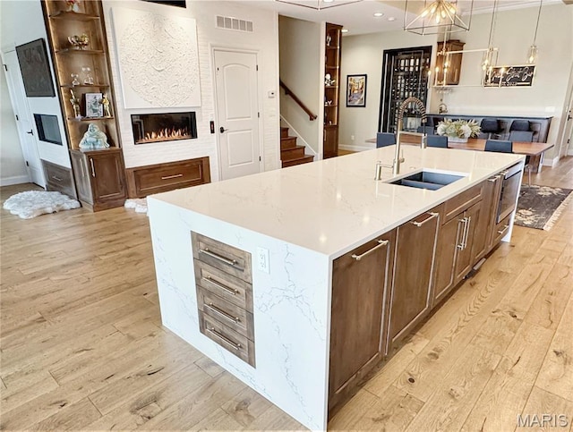 4 Market St, Washington, MO 63090 - kitchen featuring light wood-style flooring, a large fireplace, light stone countertops, a kitchen island with sink, and hanging light fixtures