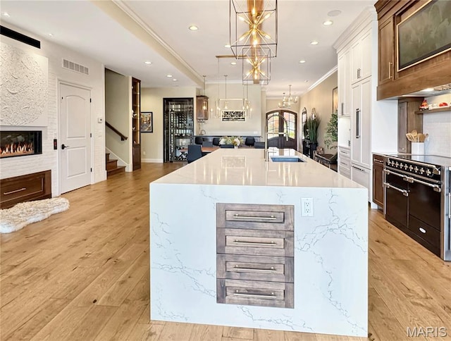 4 Market St, Washington, MO 63090 - kitchen with light wood-type flooring, pendant lighting, an island with sink, double oven range, and light stone countertops