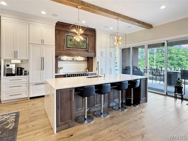 4 Market St, Washington, MO 63090 - kitchen featuring beamed ceiling, light wood-style flooring, light countertops, a center island with sink, and decorative backsplash