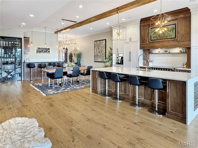 4 Market St, Washington, MO 63090 - kitchen featuring light wood-type flooring, light countertops, decorative backsplash, a large island with sink, and a kitchen bar