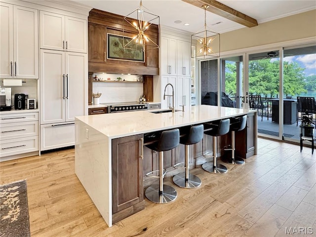 4 Market St, Washington, MO 63090 - kitchen with light wood-style floors, beam ceiling, light countertops, an island with sink, and a chandelier