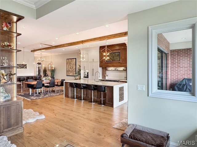 4 Market St, Washington, MO 63090 - kitchen with a chandelier, light countertops, white cabinets, light wood-style flooring, and a kitchen island with sink