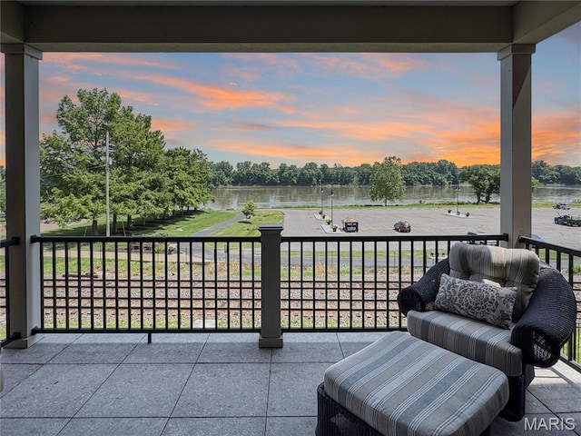 4 Market St, Washington, MO 63090 - patio terrace at dusk featuring a water view, a balcony, and view of wooded area