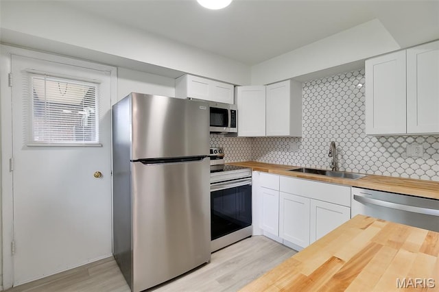 8733 Sieloff Dr Unit C, Hazelwood, MO 63042 - kitchen with wood counters, appliances with stainless steel finishes, white cabinets, tasteful backsplash, and light wood-style floors