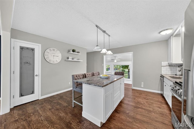 1002 Arlington Dr, Saint Charles, MO 63303 - kitchen featuring appliances with stainless steel finishes, a kitchen bar, a textured ceiling, white cabinets, and tasteful backsplash