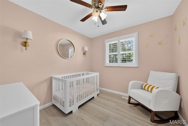 1002 Arlington Dr, Saint Charles, MO 63303 - bedroom featuring a nursery area, light wood-type flooring, and a ceiling fan