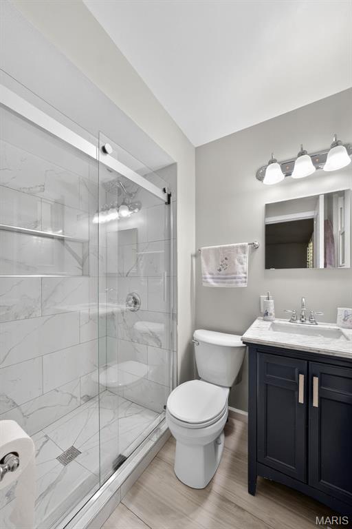 1002 Arlington Dr, Saint Charles, MO 63303 - full bath featuring a stall shower, vanity, and wood finished floors