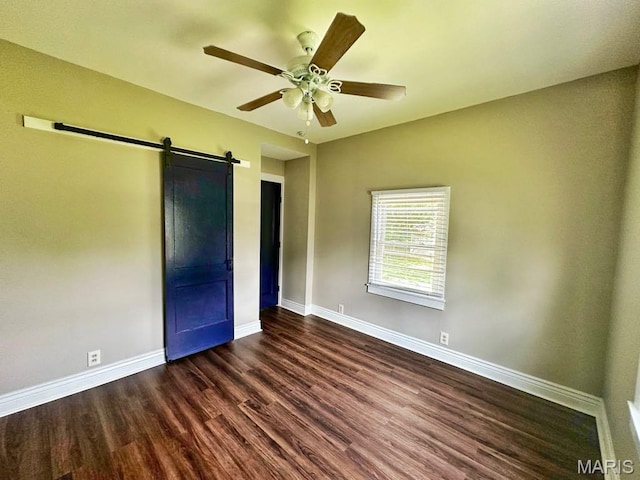 1604 Quendo Ave, Saint Louis, MO 63130 - unfurnished bedroom with dark wood-type flooring, a barn door, and a ceiling fan