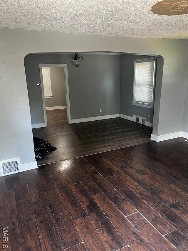 5209 College Ave, Jennings, MO 63136 - unfurnished room with wood-type flooring, a textured ceiling, and arched walkways