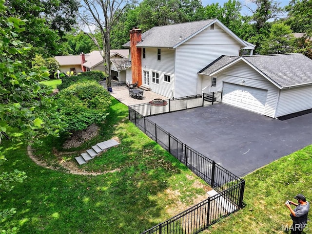 538 Kenilworth Ln, Ballwin, MO 63011 - back of property featuring a chimney, asphalt driveway, a garage, roof with shingles, and a patio