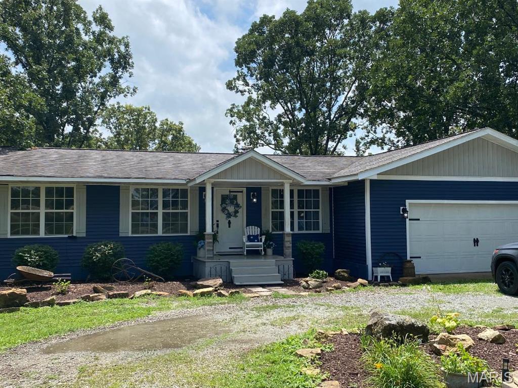 9262 State Route Aa, Farmington, MO 63640 - ranch-style home with an attached garage, a porch, dirt driveway, and roof with shingles
