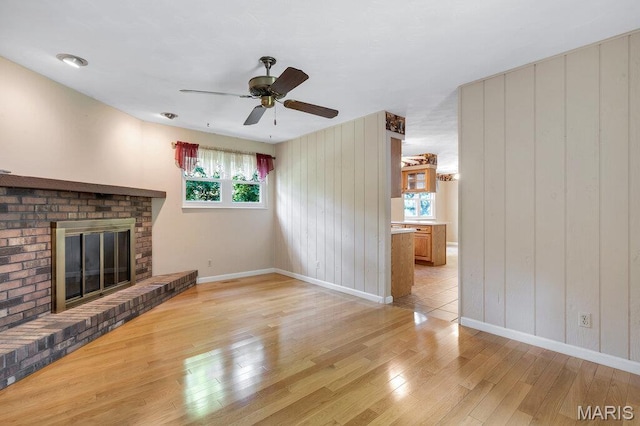 127 Hilltop Trl, Eureka, MO 63025 - unfurnished living room with light wood finished floors, a ceiling fan, a fireplace, and wood walls