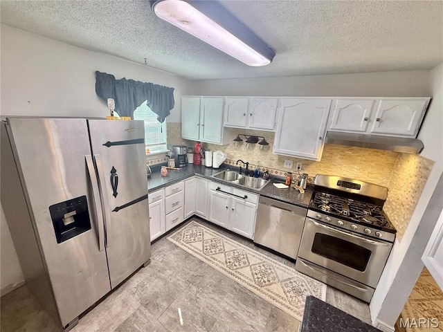 2284 Sunnyridge Dr, Arnold, MO 63010 - kitchen with appliances with stainless steel finishes, under cabinet range hood, white cabinetry, dark countertops, and a textured ceiling