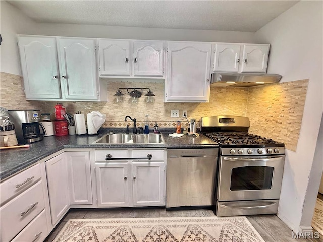 2284 Sunnyridge Dr, Arnold, MO 63010 - kitchen featuring appliances with stainless steel finishes, under cabinet range hood, white cabinets, dark countertops, and tasteful backsplash