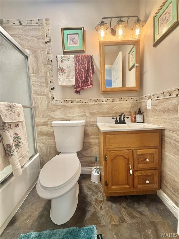2284 Sunnyridge Dr, Arnold, MO 63010 - bathroom with vanity, tile walls, bath / shower combo with glass door, and a wainscoted wall