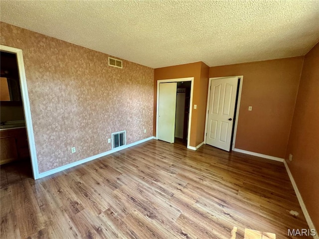 5250 Wren Ln, Osage Beach, MO 65065 - unfurnished bedroom with wood finished floors, a textured ceiling, and a closet