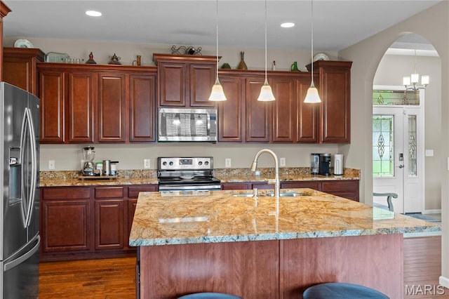 9882 W Vista Dr, Hillsboro, MO 63050 - kitchen with appliances with stainless steel finishes, dark wood-style flooring, arched walkways, light stone counters, and a breakfast bar
