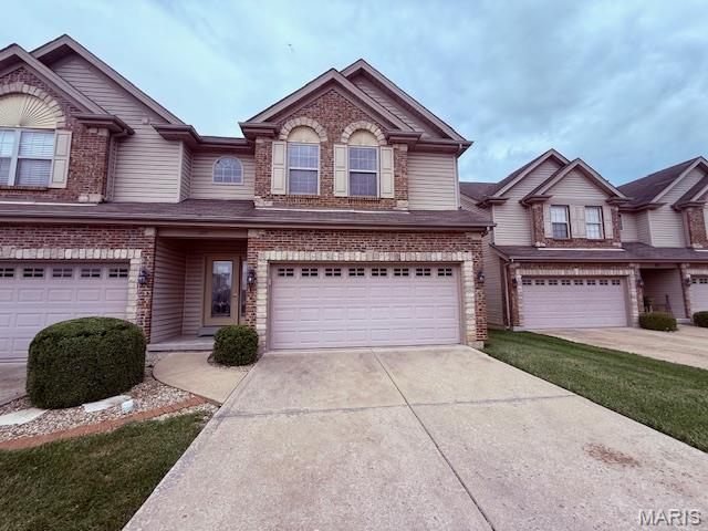 205 Prominence Ln, Lake St Louis, MO 63367 - view of front of house featuring an attached garage, concrete driveway, and brick siding