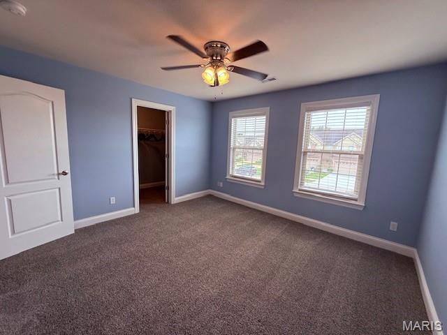 205 Prominence Ln, Lake St Louis, MO 63367 - unfurnished bedroom featuring dark colored carpet, a spacious closet, and a ceiling fan