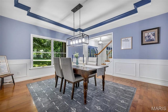 16517 Lancaster Estates Dr, Grover, MO 63040 - dining area featuring stairs, a wainscoted wall, hardwood / wood-style flooring, a raised ceiling, and a chandelier