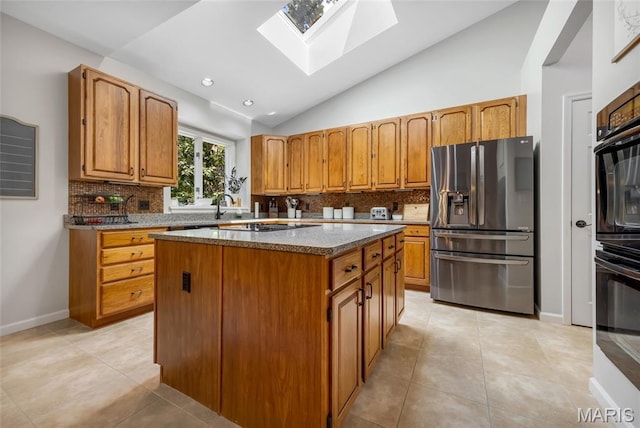 16517 Lancaster Estates Dr, Grover, MO 63040 - kitchen with stainless steel fridge, a skylight, a kitchen island, vaulted ceiling, and tasteful backsplash