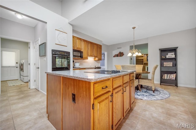 16517 Lancaster Estates Dr, Grover, MO 63040 - kitchen with black appliances, independent washer and dryer, a chandelier, light tile patterned floors, and decorative light fixtures