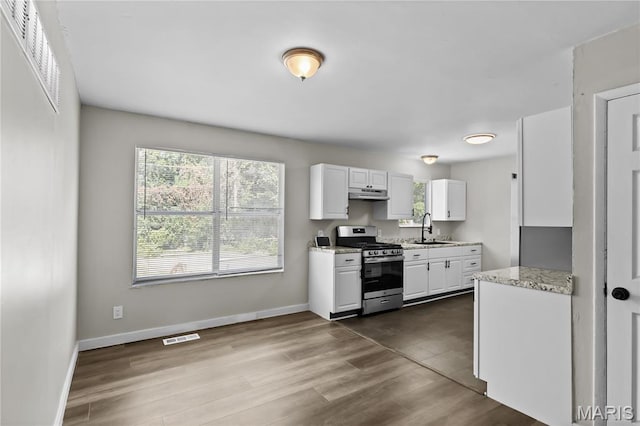 10411 Royal Dr, Saint Louis, MO 63136 - kitchen featuring stainless steel gas range, under cabinet range hood, white cabinetry, and dark wood finished floors