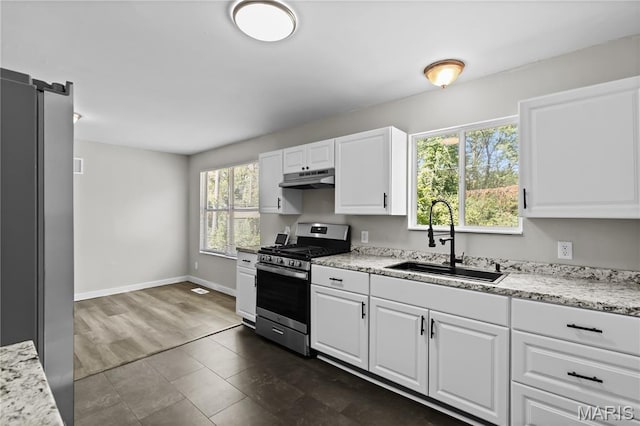 10411 Royal Dr, Saint Louis, MO 63136 - kitchen with stainless steel gas range, under cabinet range hood, white cabinetry, and light stone countertops