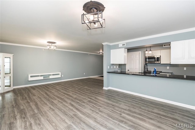 3624 Colonia Pl Unit B, Saint Louis, MO 63125 - kitchen featuring stainless steel microwave, ornamental molding, dark countertops, white cabinets, and wood finished floors