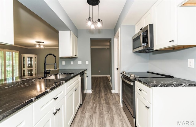 3624 Colonia Pl Unit B, Saint Louis, MO 63125 - kitchen featuring appliances with stainless steel finishes, light wood finished floors, dark stone counters, white cabinetry, and decorative light fixtures