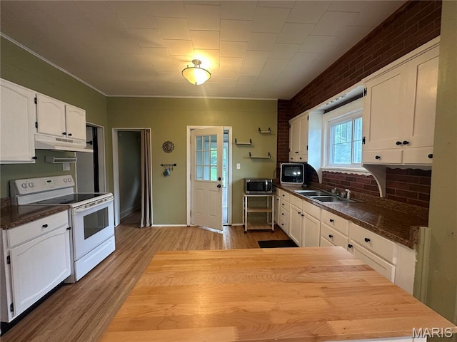 806 Pleasant St, Hannibal, MO 63401 - kitchen with white range with electric cooktop, stainless steel microwave, under cabinet range hood, wood finished floors, and white cabinetry