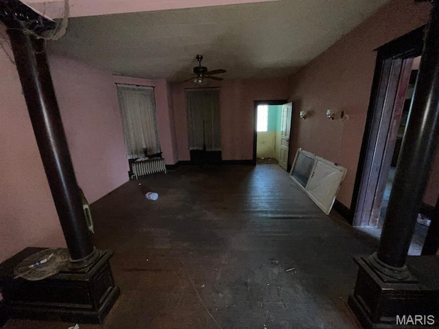 1063 Hornsby Ave, Saint Louis, MO 63147 - unfurnished living room featuring radiator, ceiling fan, ornate columns, and a wood stove